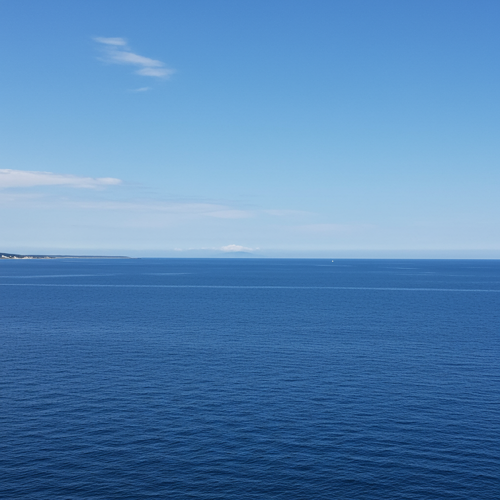 Serene Atlantic Ocean surface under a clear early June sky, with a faint, distant atmospheric swirl hinting at underlying forces, representing the quiet start to hurricane season contrasting with Pacific activity.